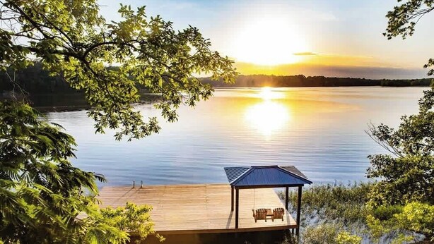 A wooden dock extending into a calm lake with a sunset in the background. - Lake T Retreat - Sunset - Pool - Putting Green! (Northport)