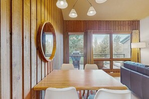 Enjoy meals at the large dining table surrounded by comfortable chairs, with a sofa nearby for relaxing.