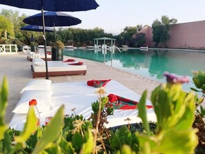 A poolside area with lounge chairs, umbrellas, and a pool. - Relais d'ourika (Oulad Dlim)