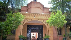 A traditional building with an ornate entrance, potted plants, and a gravel pathway. - Relais d'ourika (Oulad Dlim)