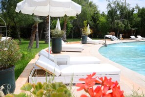 A poolside area with lounge chairs and umbrellas, surrounded by greenery. - Relais d'ourika (Oulad Dlim)