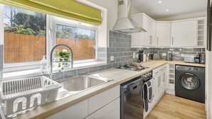 A modern kitchen with a large window, built-in appliances, and a wooden floor. - Luxury House in Bristol with Hot Tub - Sleeps 10 (Bristol)