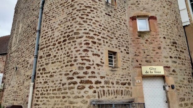Un bâtiment en pierre doté d’une tour ronde, d’une petite fenêtre et d’une enseigne indiquant « Gîte de la Tour ».
