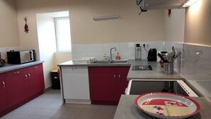 Une cuisine avec des meubles de rangement rouges et blancs, un four à micro-ondes, un évier et une machine à café.