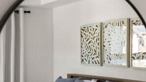 A bedroom with a bed, pillows, a headboard, and a decorative wall piece. - Tranquil Waterside | Pool & Hot Tub | Renovated (Invermere)