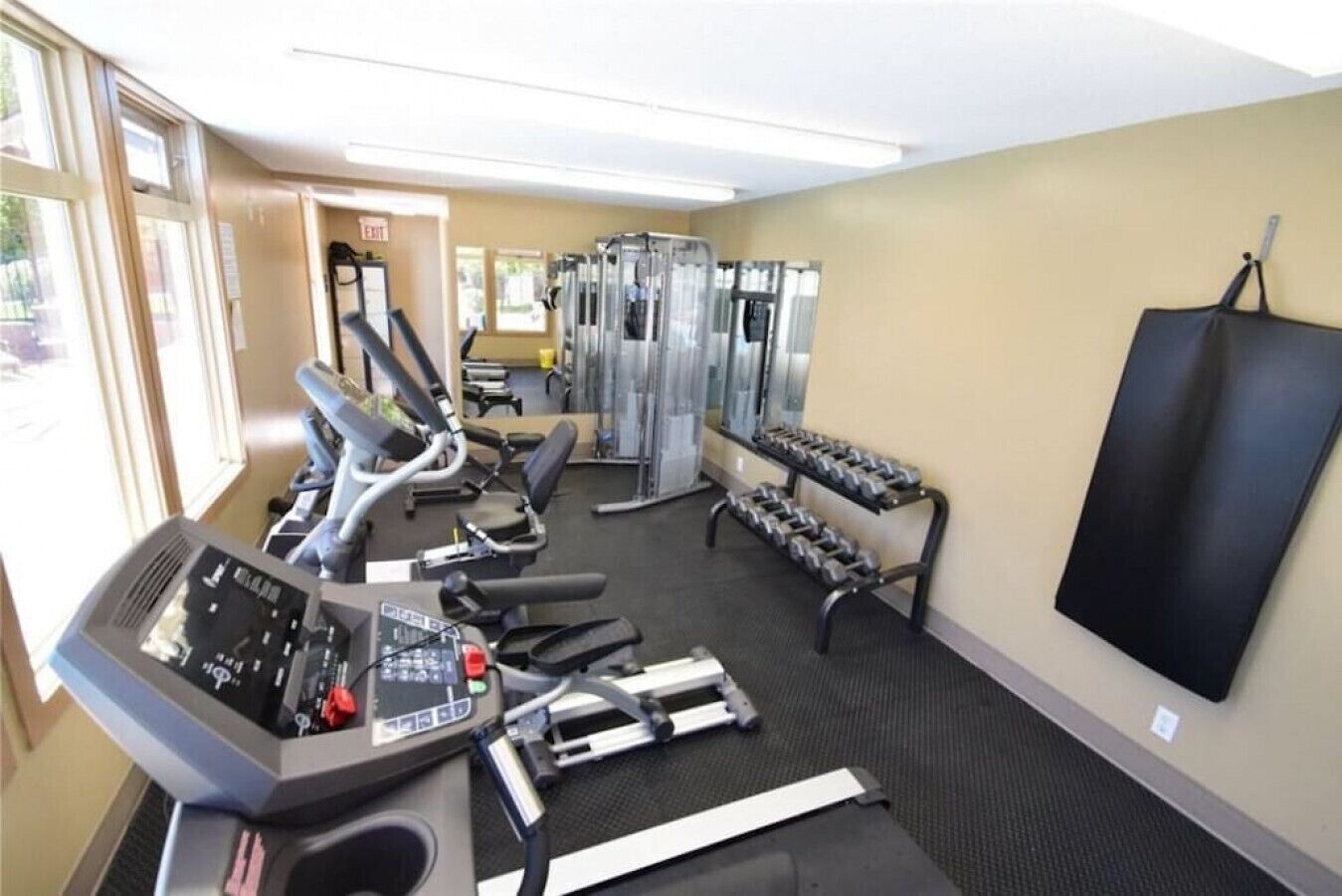 Une salle de sport équipée de tapis de course, d’appareils de musculation et d’haltères.