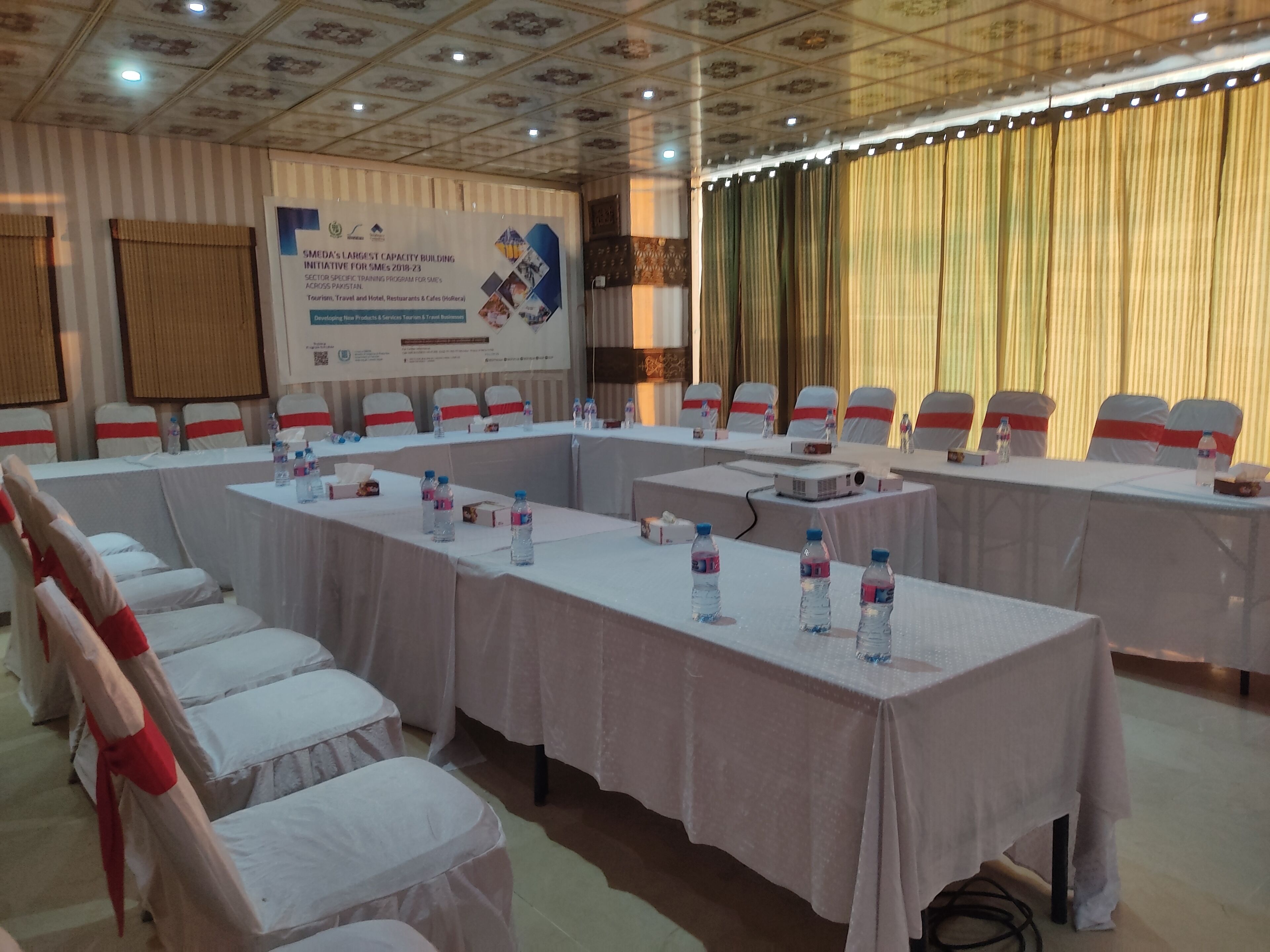 A conference room with long tables, chairs, and a banner on the wall.