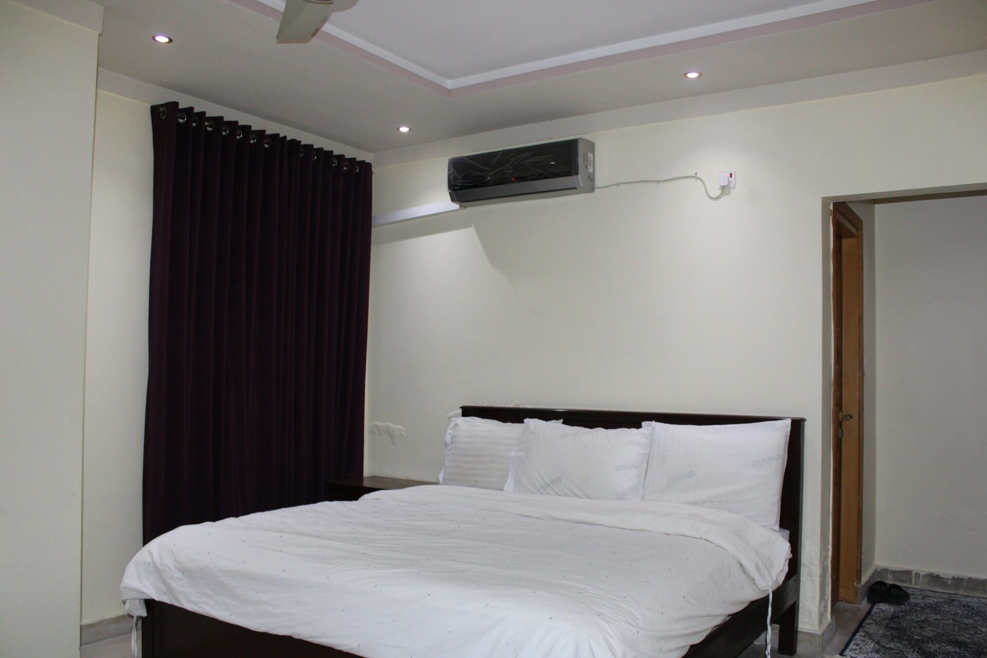 Un dormitorio con una cama, aire acondicionado de pared y una puerta.
