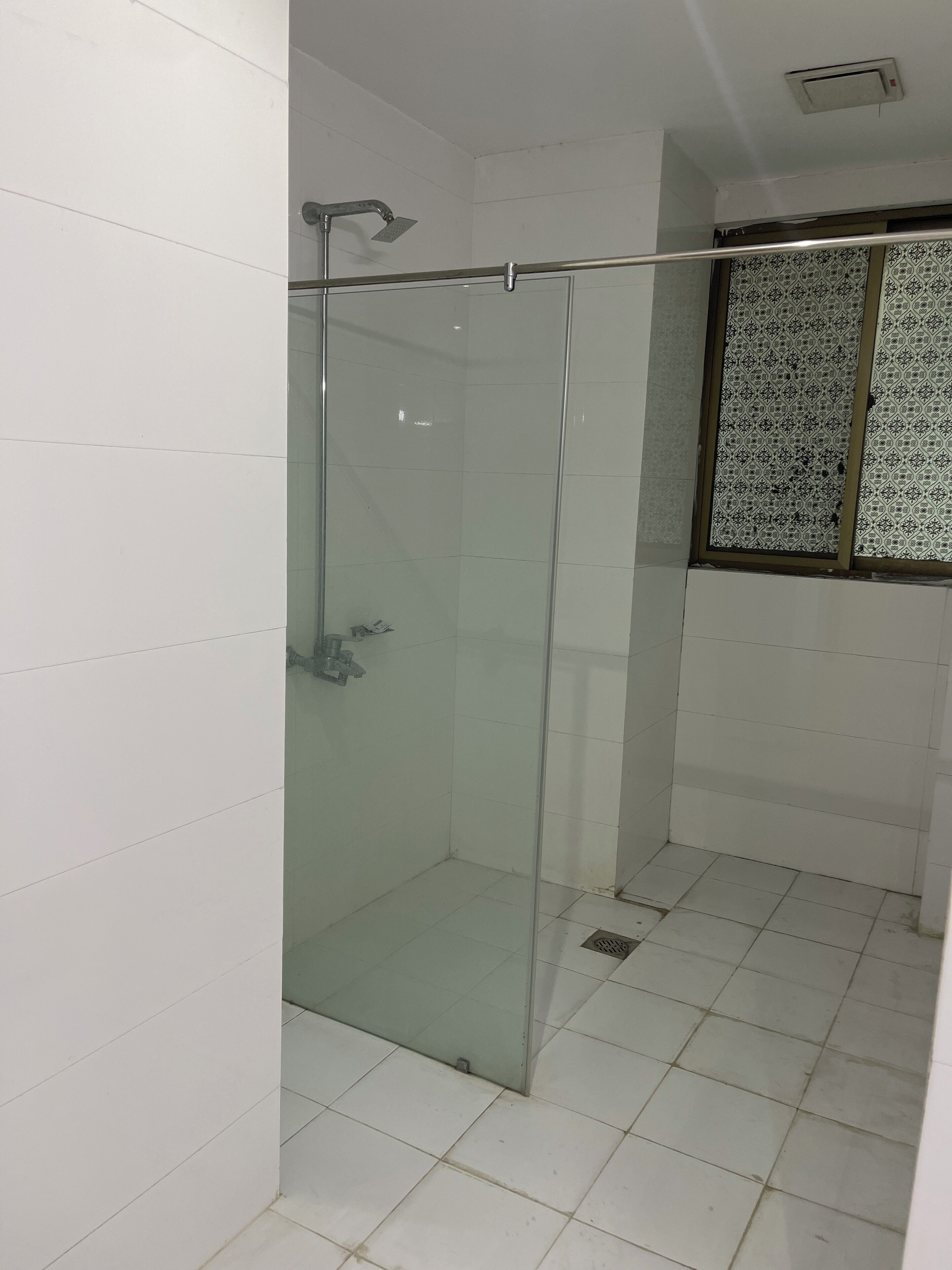 A glass-enclosed shower stall with a metal showerhead and a glass door.