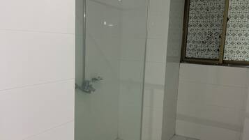 A glass-enclosed shower stall with a metal showerhead and a glass door.