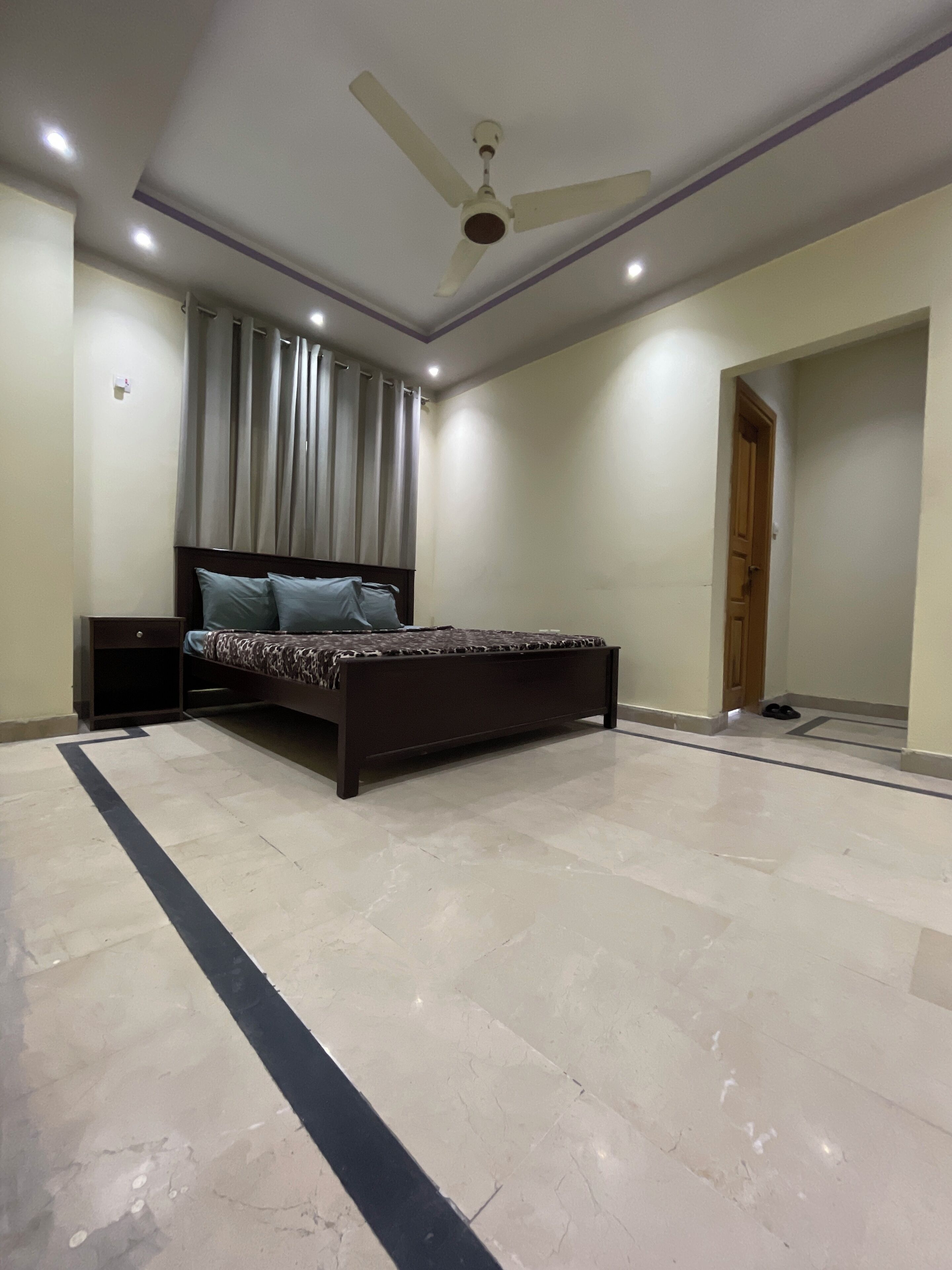 A bedroom with a bed, a ceiling fan, and a door.