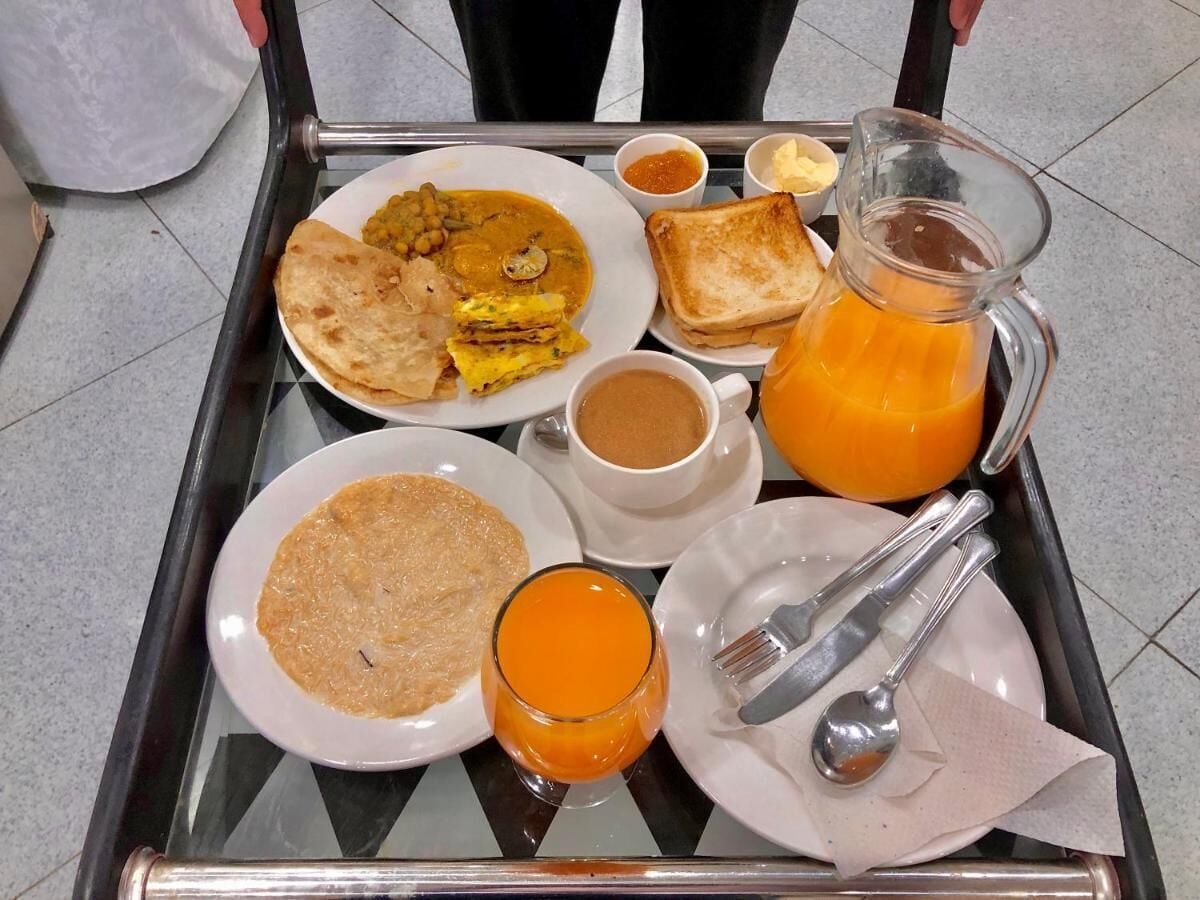 A tray with breakfast items including toast, a jug of orange juice, a plate of eggs, and a cup of coffee.