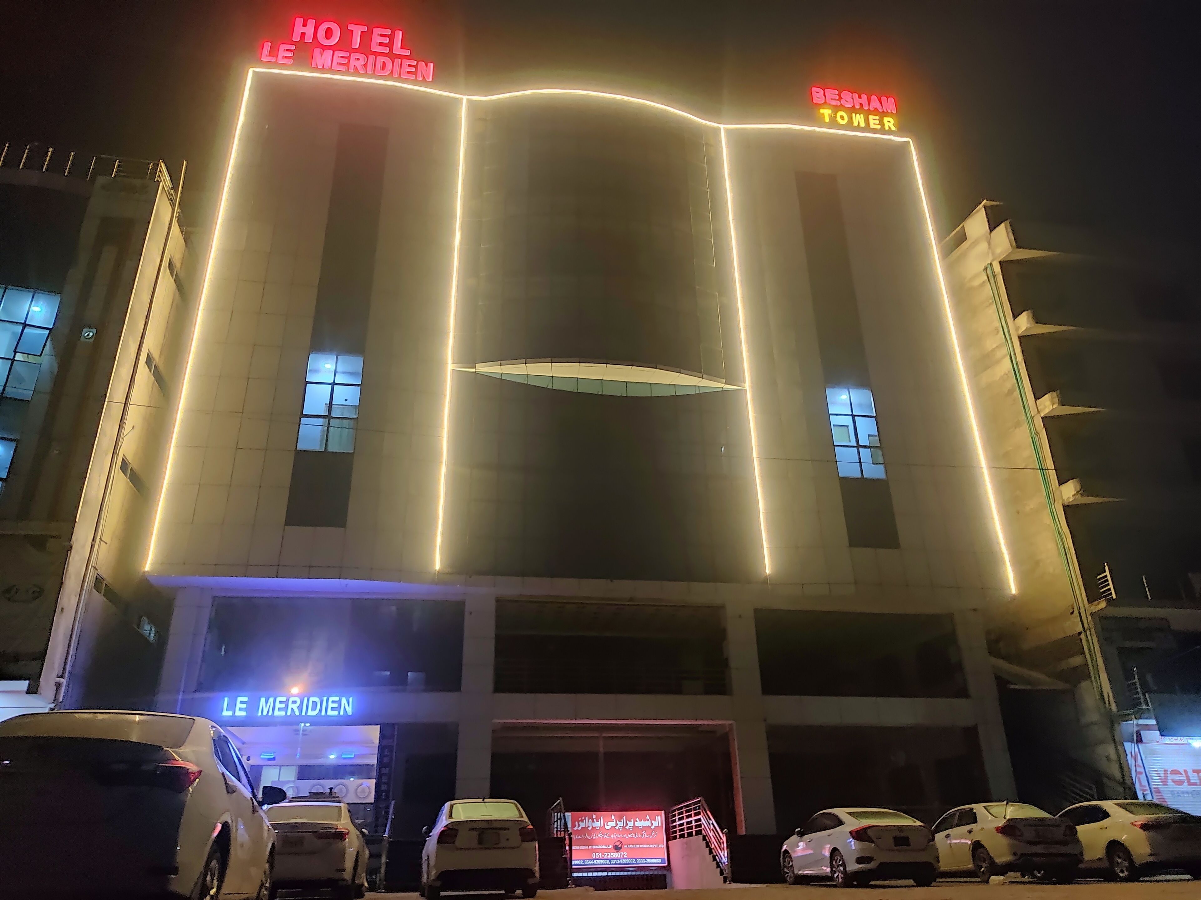 Ein Hotel mit beleuchteter Beschilderung mit der Aufschrift "HOTEL LE MERIDIEN" und "BESHAM TOWER".