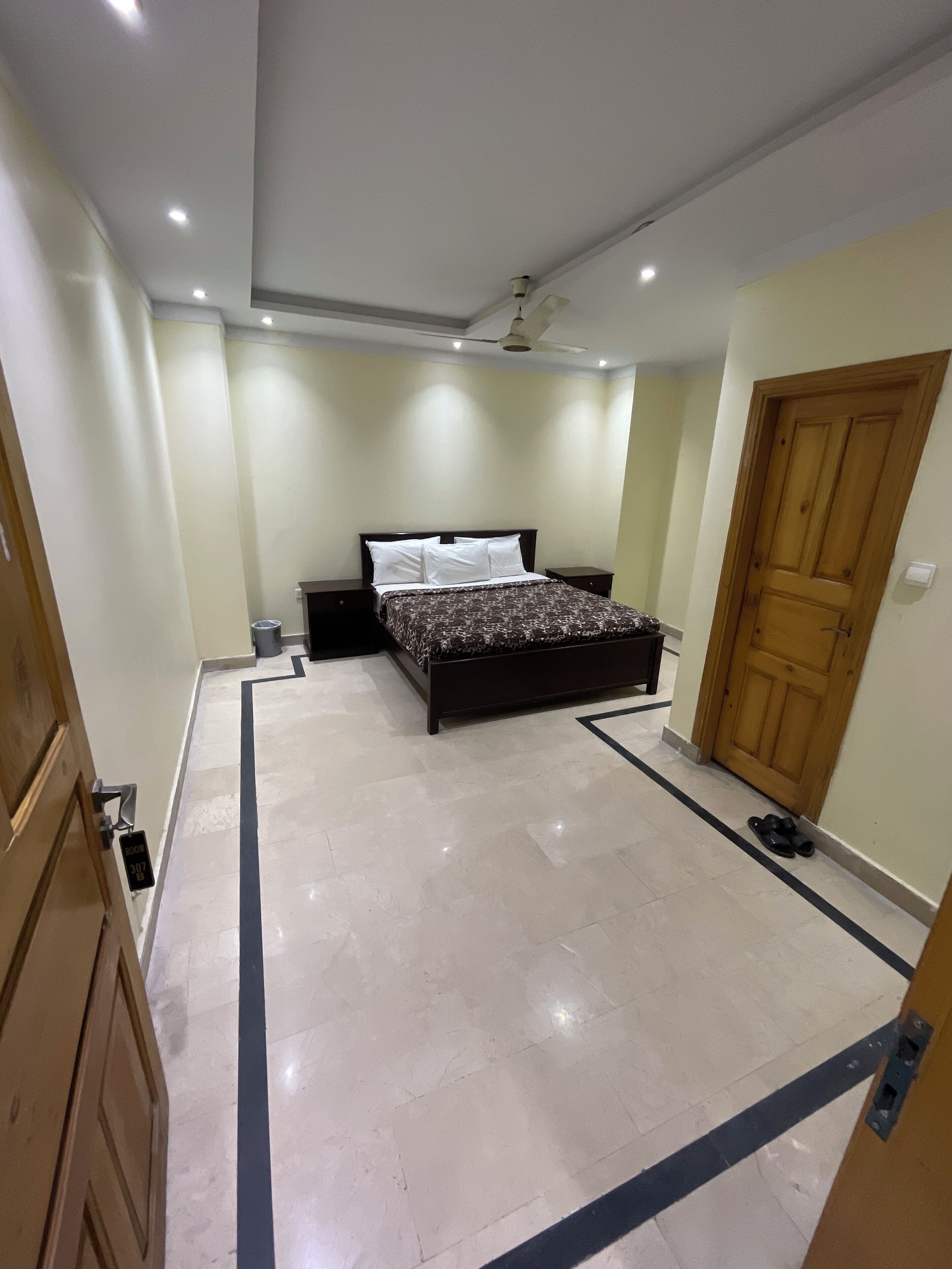 A spacious bedroom with a large bed, a ceiling fan, and a wooden door.