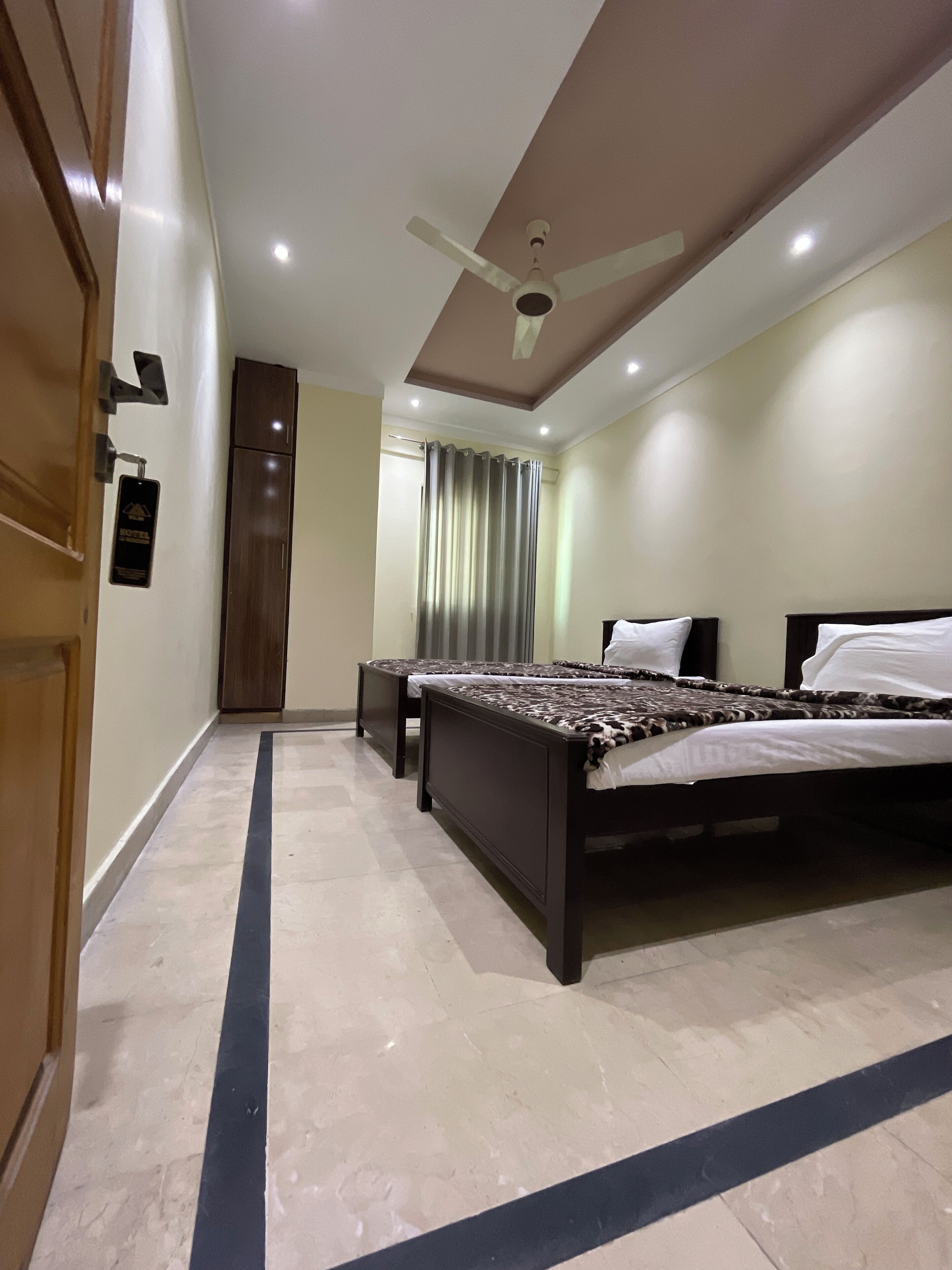 A hotel room with a large bed, a ceiling fan, and a bathroom door.