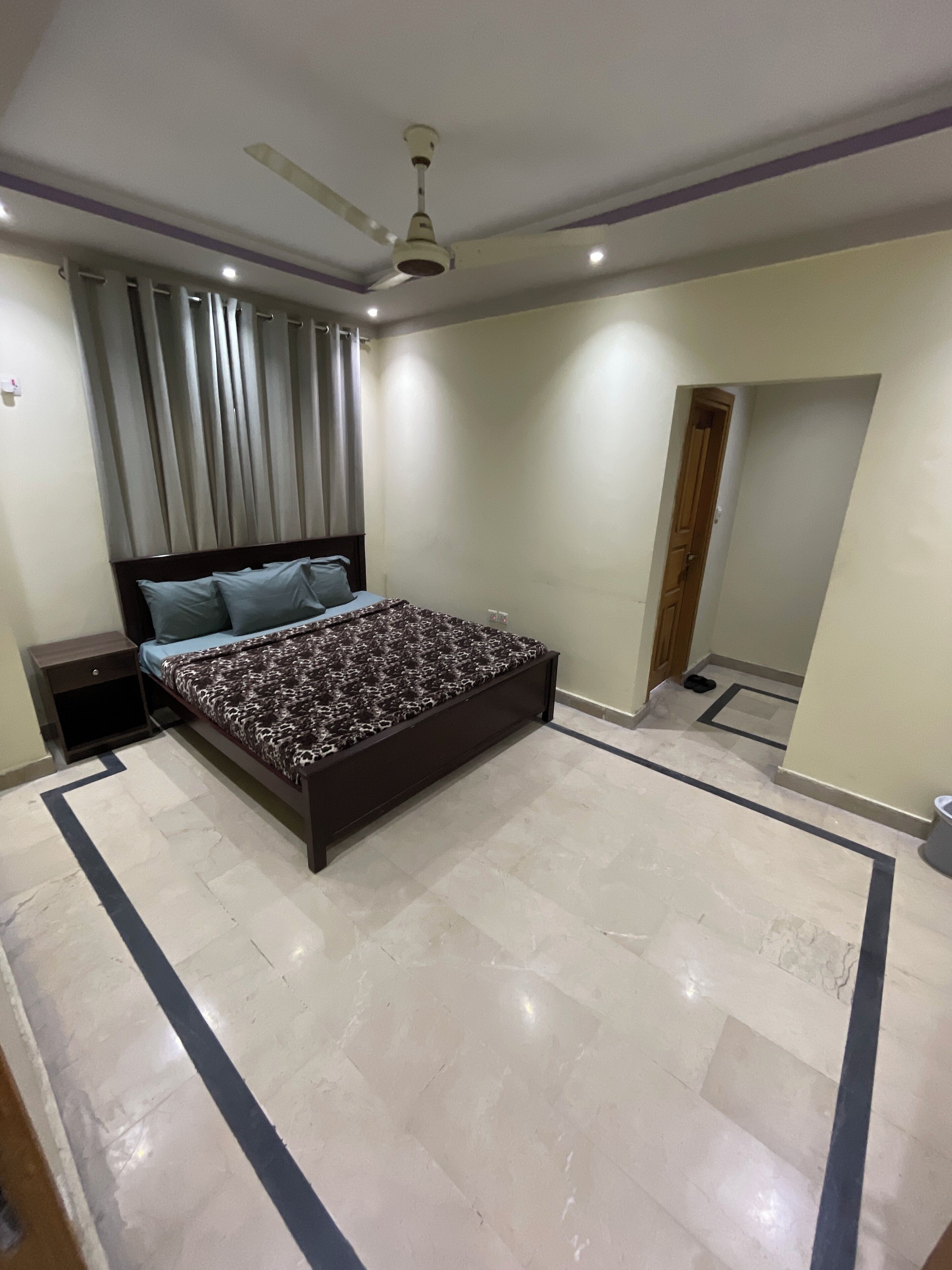 A bedroom with a large bed, a ceiling fan, and a mirror on the wall.