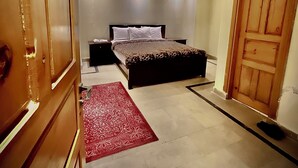 Een slaapkamer met een bed, een plafondventilator, een rood tapijt en een houten deur.