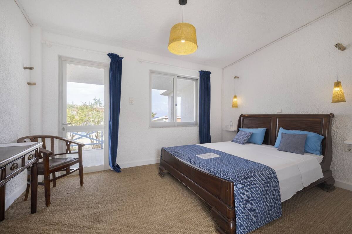 A bedroom with a bed, a desk, and a chair.