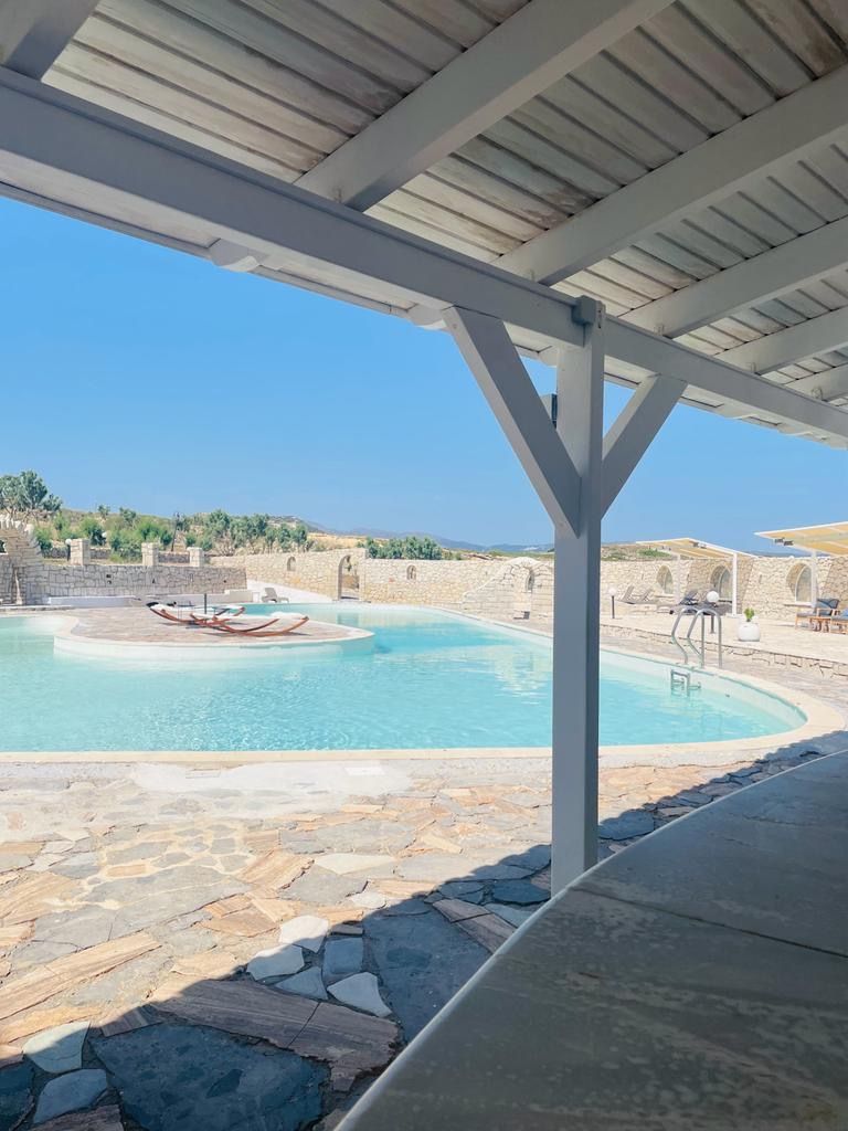 A pool area with stone flooring, a covered section, and a view of the landscape.