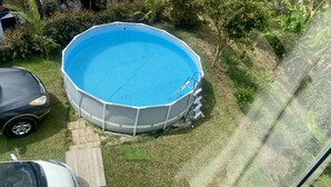 Una piscina elevada con superficie de azulejos azules, rodeada por una valla blanca.