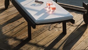A sunlit outdoor lounge chair with a white cushion, two glasses of pink drink, and a pair of sunglasses on the seat. - ---Ammira Mare--House near sea with pool (Malevizi)