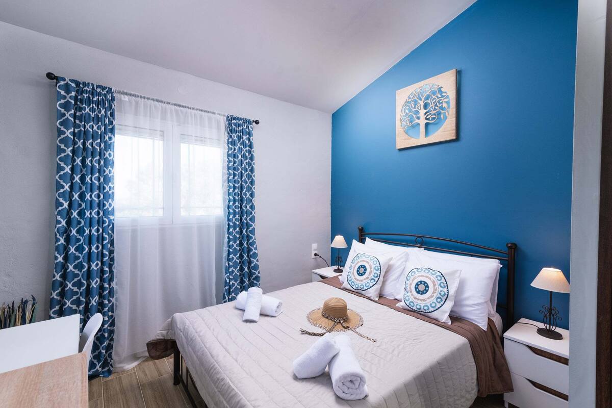 Une chambre bien rangée, avec un lit, des oreillers, un chapeau et des serviettes.