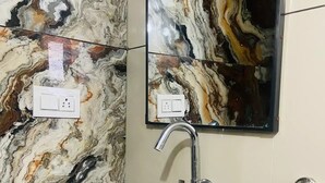 A bathroom with a white sink, a mirror, and a marble backsplash.
