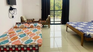 A room with two beds, a TV, a desk, and a window with curtains.