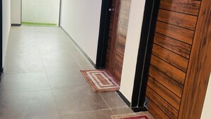 A hallway with a tiled floor, a wooden door, and a door mat.