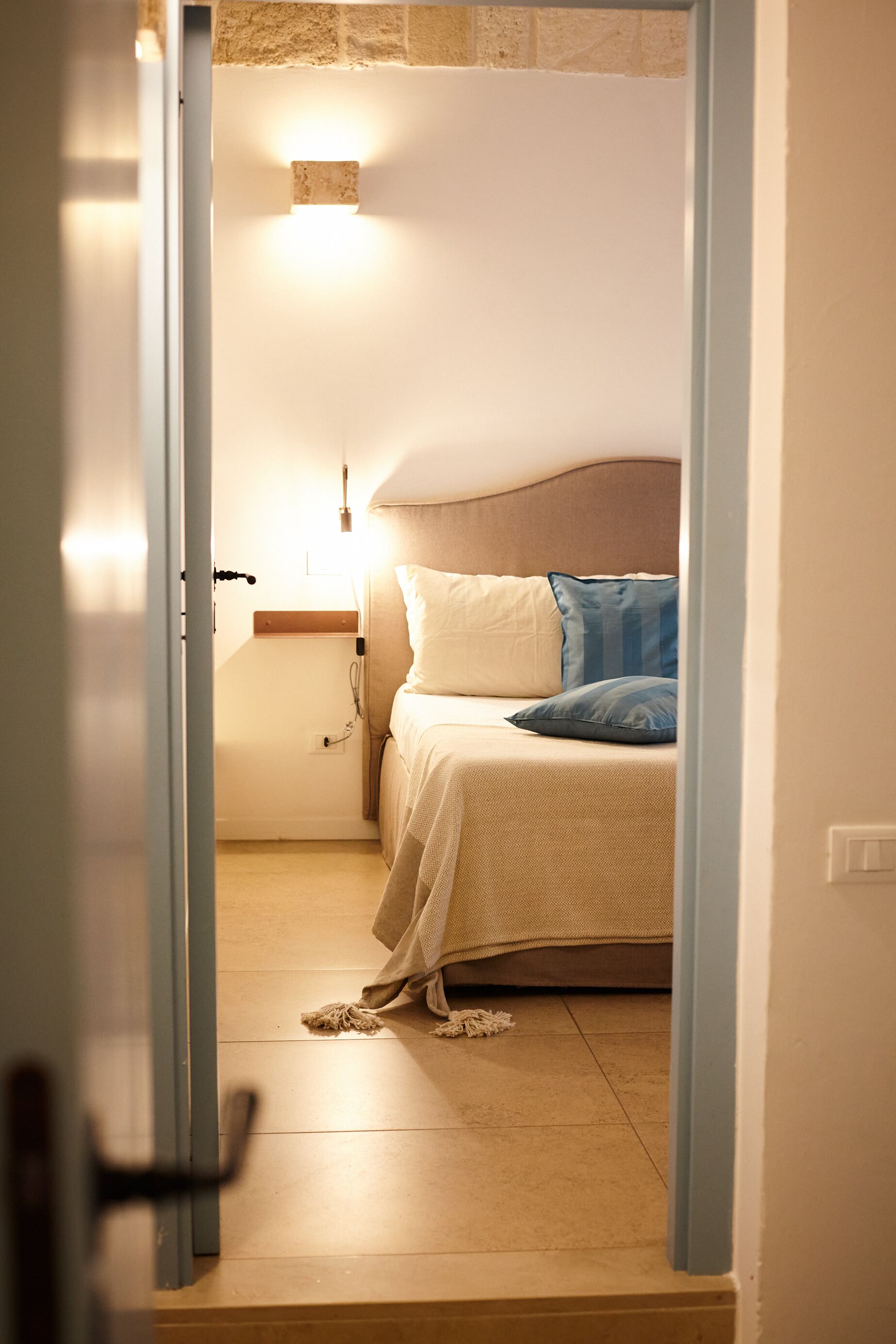 Une chambre à coucher avec un lit, une table de chevet et un luminaire fixé au mur.