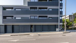 A modern multi-story building with a flat facade, large windows, and a clean, urban street in front. - Nomads Lux - 2BDR Parking Flores Porto (Porto)