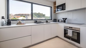 A modern kitchen with a large window, built-in microwave, oven, and a coffee machine. - Nomads Lux - 2BDR Parking Flores Porto (Porto)