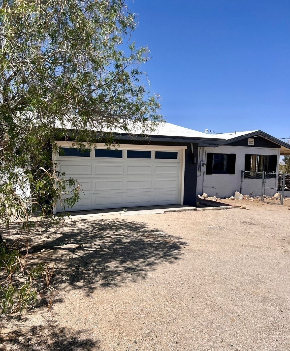 A single-story house with a white garage door, a small attached garage, and a clear sky.