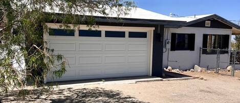A single-story house with a white garage door, a small attached garage, and a clear sky.