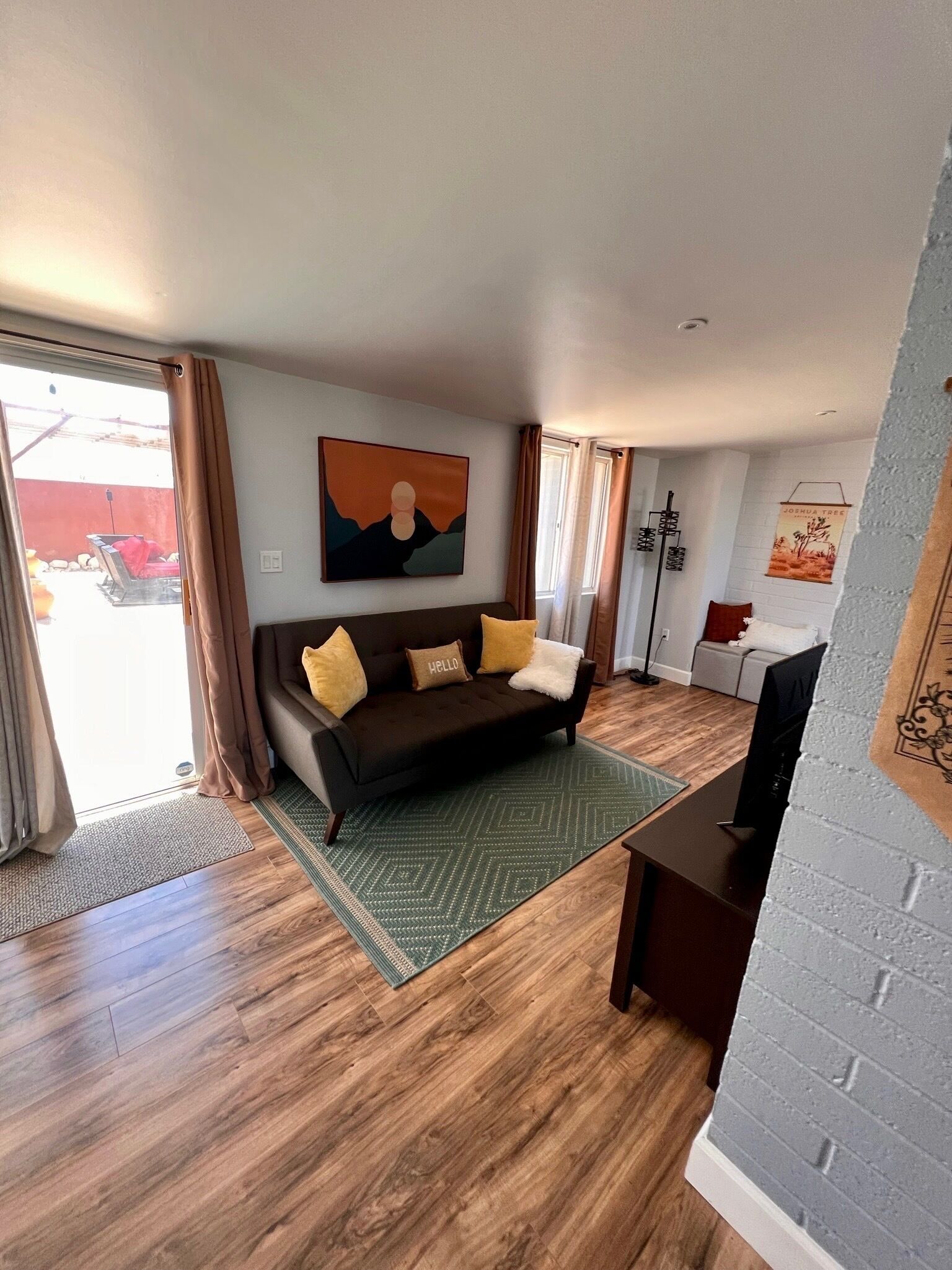 A living room with a dark brown sofa, a green patterned rug, and a painting on the wall.