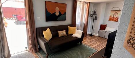 A living room with a dark brown sofa, a green patterned rug, and a painting on the wall.