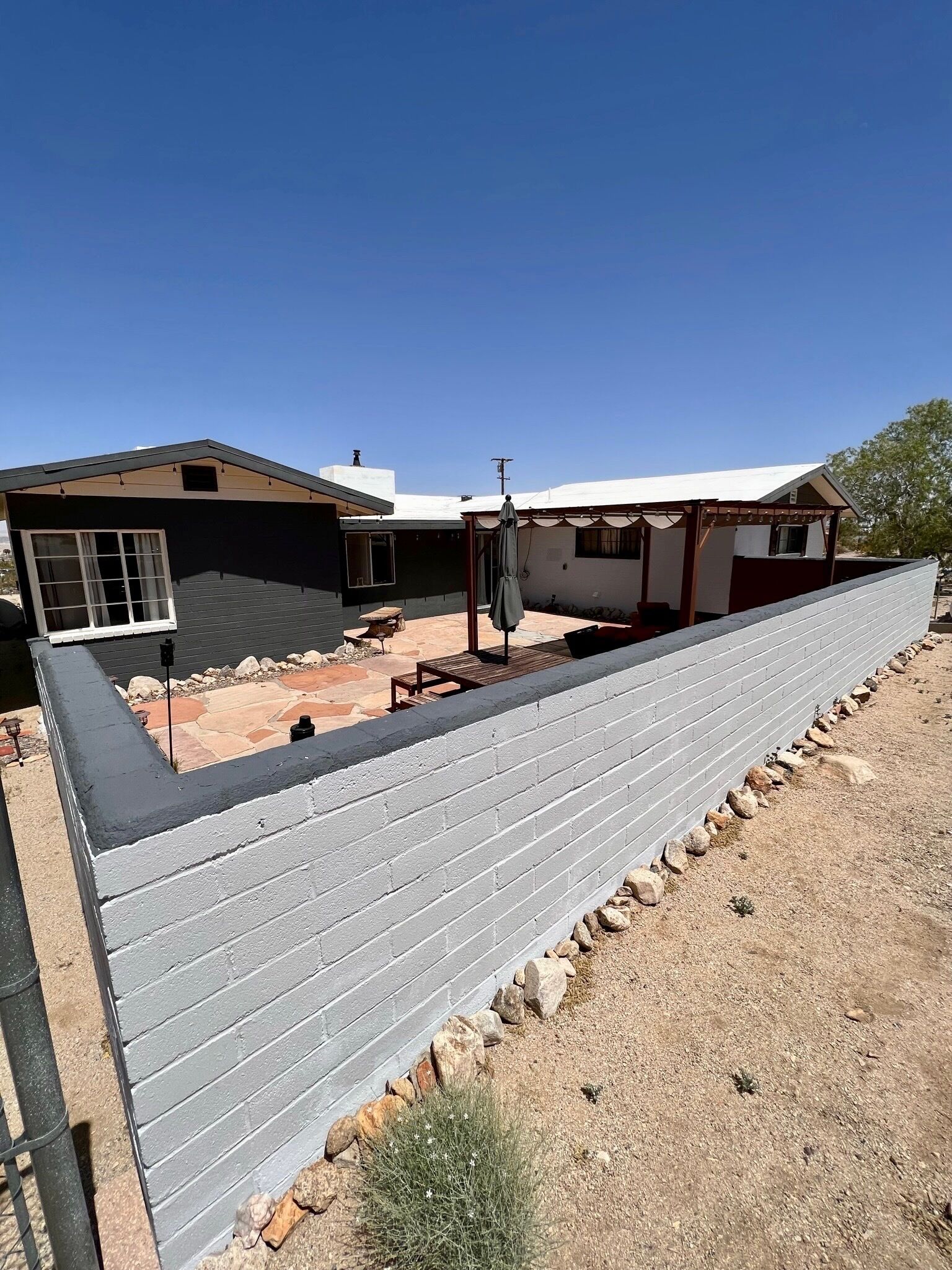 A house with a covered patio, a fenced backyard, and a clear blue sky.