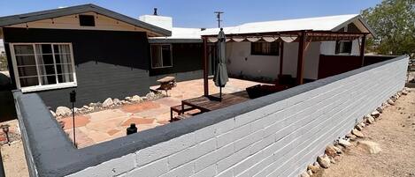 A house with a covered patio, a fenced backyard, and a clear blue sky.