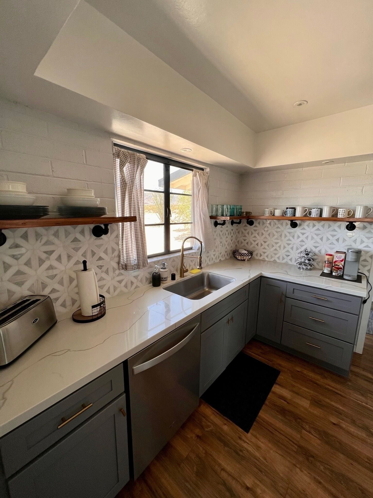 A modern kitchen with grey cabinets, a stainless steel sink, and a wooden countertop.
