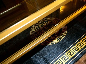 A close-up of a black and gold patterned carpet with a geometric design. - Deluxe Versace Styled Apartment (South Yorkshire)
