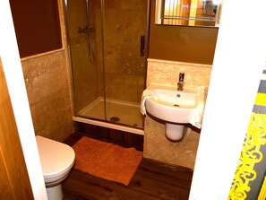A bathroom with a toilet, a shower with a glass door, and a sink with a towel hanging on it. - Deluxe Versace Styled Apartment (South Yorkshire)