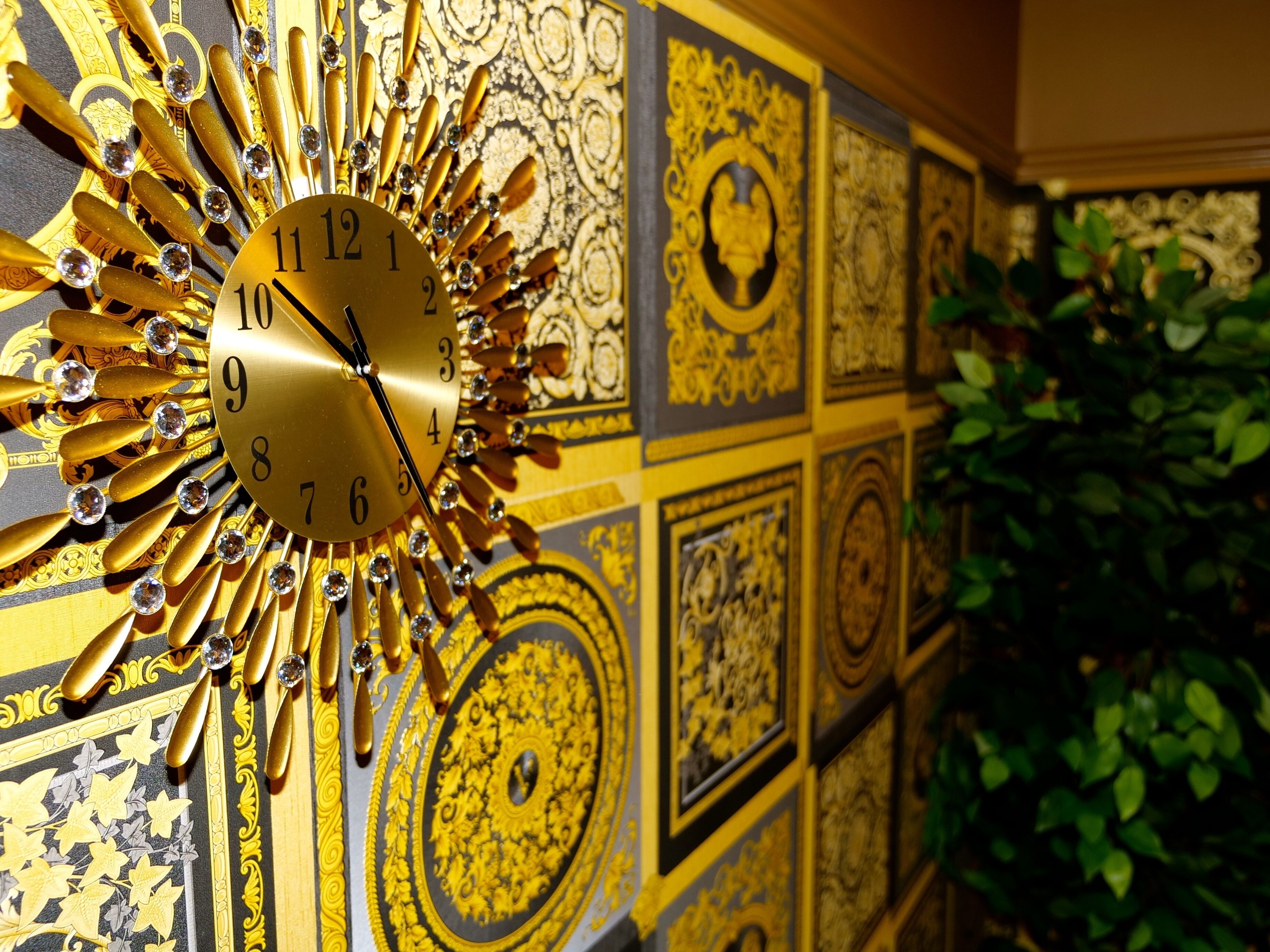 A wall with a large, ornate clock featuring gold accents and crystal decorations.