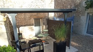 An outdoor patio with a grill, seating, and a potted plant. - L'instant Civray (Civray sur esves)
