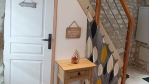 A wooden staircase with a leaf-patterned wall hanging, a white door with a 'TOILETTES' sign, and a small wooden table with a decorative item. - L'instant Civray (Civray sur esves)