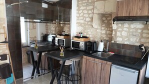 A compact kitchen with a stone wall, a built-in oven, a microwave, and a coffee maker. - L'instant Civray (Civray sur esves)
