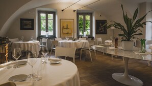 Un comedor con mesas redondas, sillas y una planta en maceta.