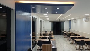 Una aula amb files de taules i cadirees, una pissarra i un projecte.