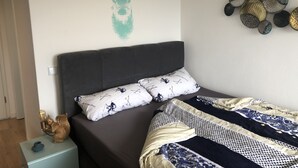 A bedroom with a bed, a nightstand, a wall art piece, and a decorative wall hanging.