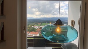 A room with a view of a town and mountains through a large window.