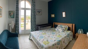 A bedroom with a bed, a chair, a desk, and a window with curtains.